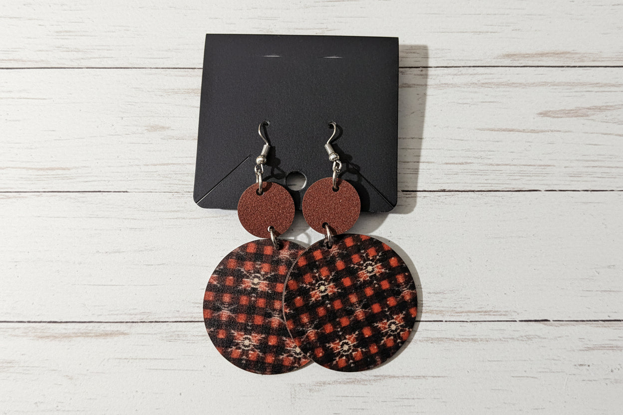 Pair of round earrings with patterned backs on a dark surface