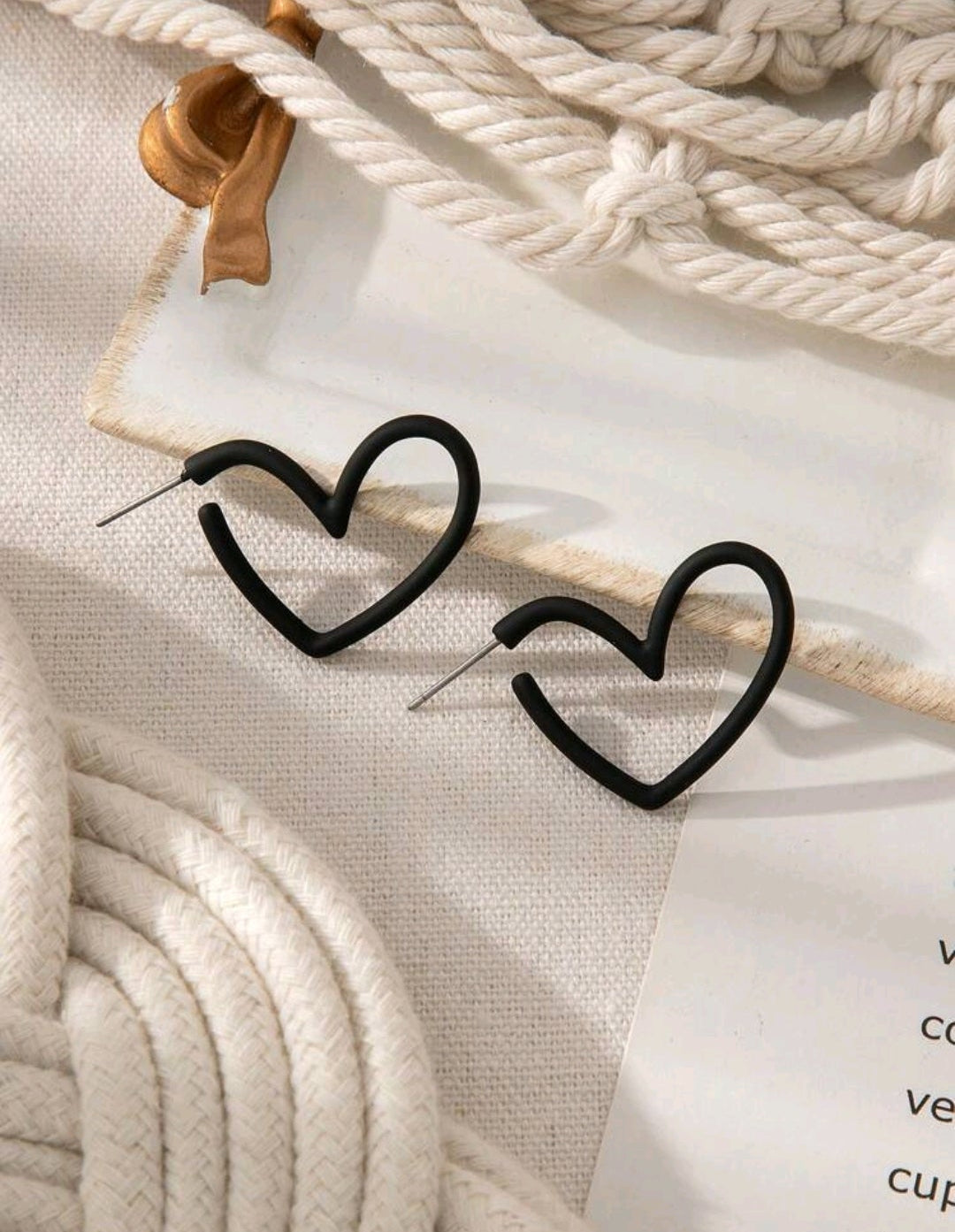Heart-shaped earrings on a textured surface with a blurred background