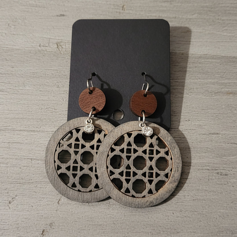 Wooden earrings with geometric patterns on a wooden surface
