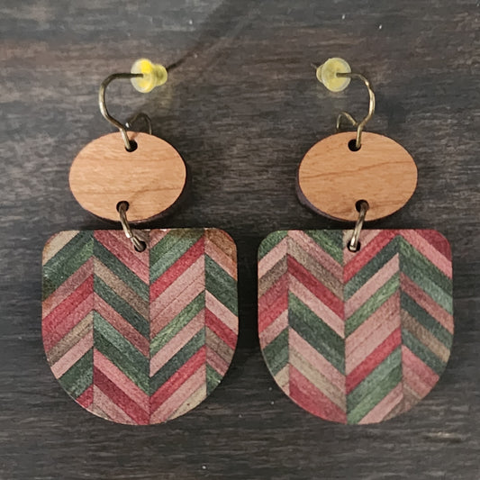 Wooden earrings with chevron pattern on a wooden surface