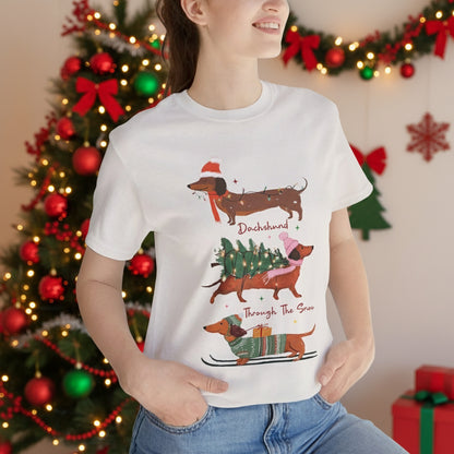 Person wearing a white t-shirt with Christmas-themed dachshund graphics.