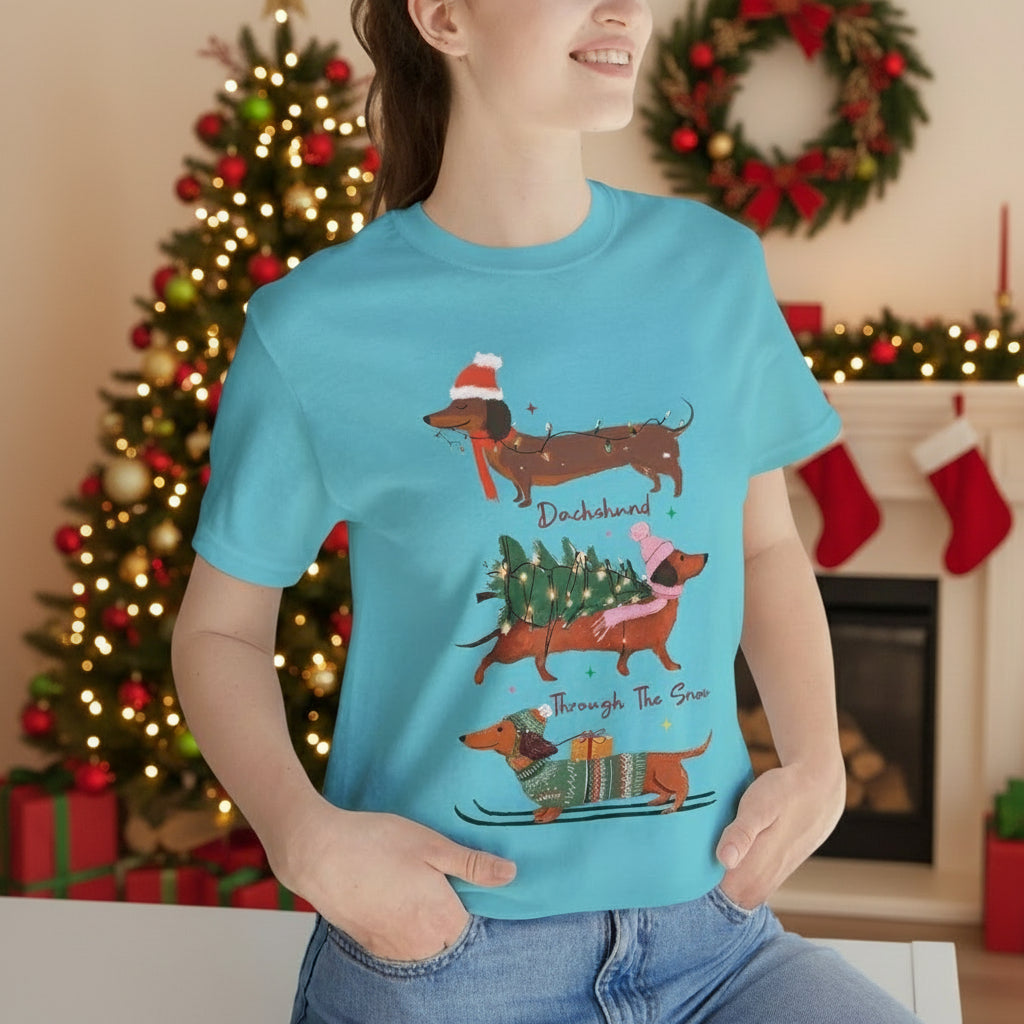 Person wearing a blue t-shirt with Christmas-themed dachshund illustrations.