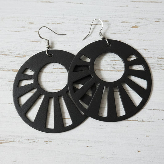 Pair of black metal earrings on a wooden surface