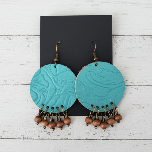 Turquoise earrings with wooden beads on a wooden surface