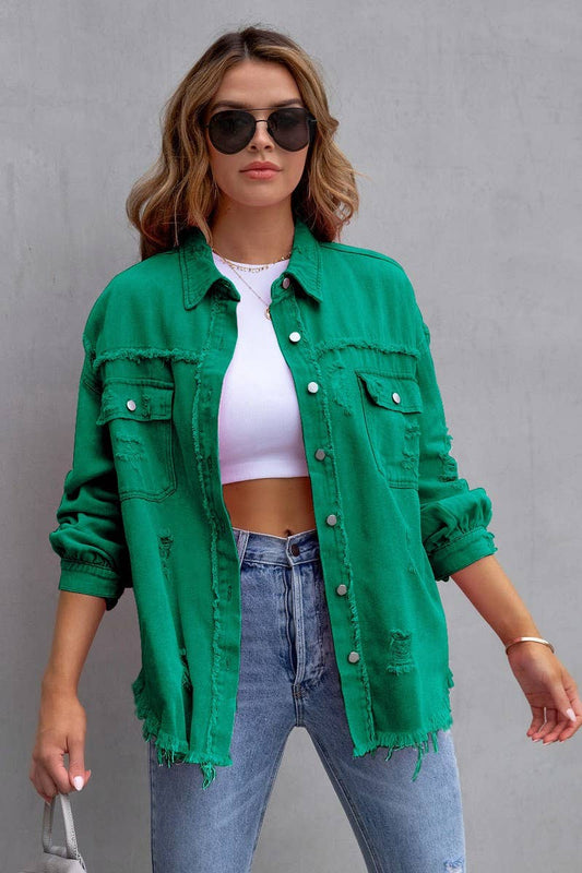 Woman wearing a green denim jacket, white crop top, and blue jeans against a gray background