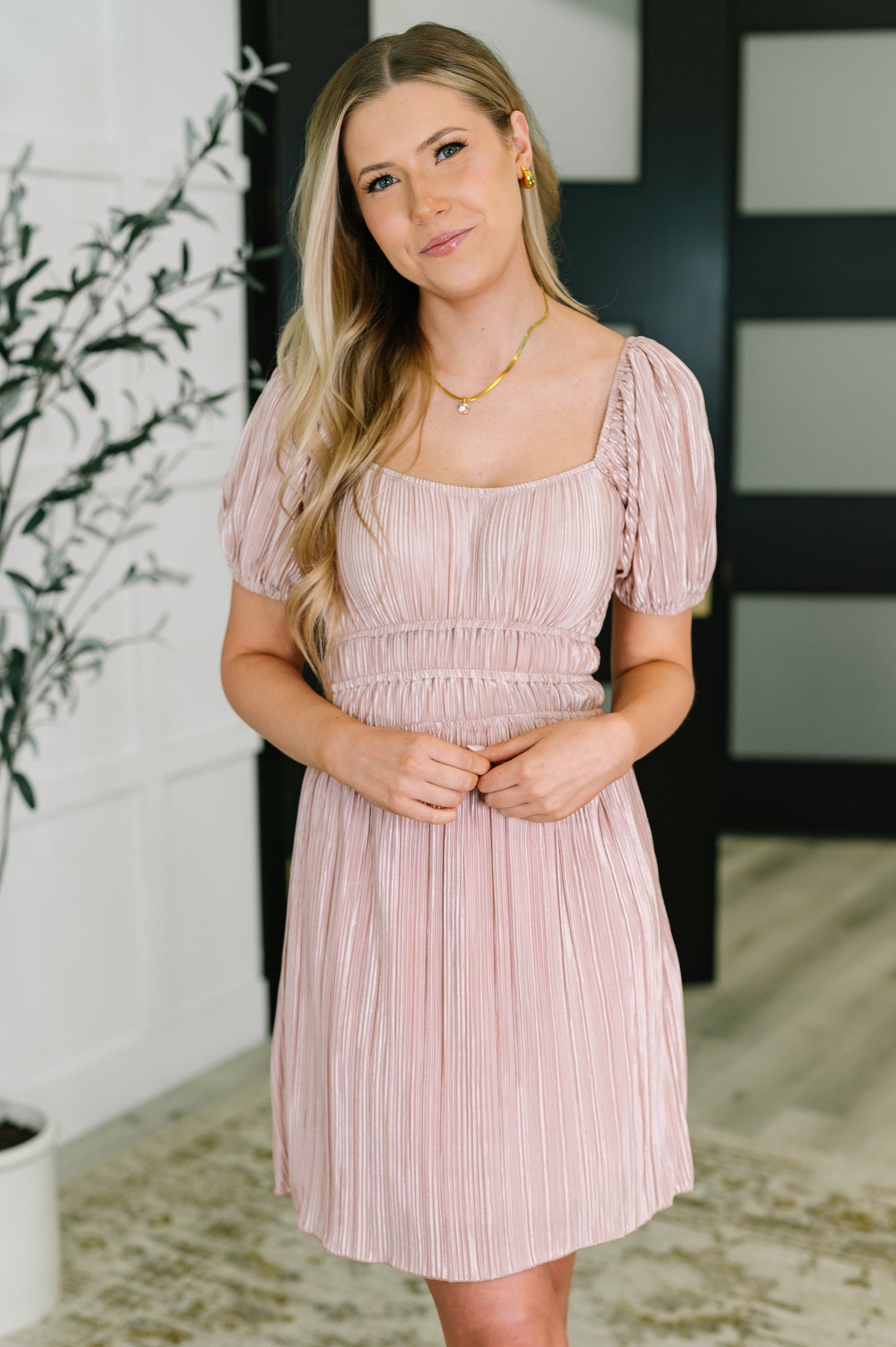 Woman wearing a light pink dress with a blurred indoor background
