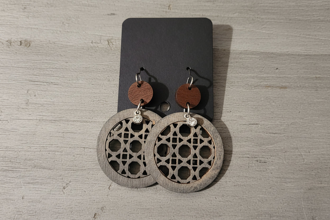 Wooden earrings with geometric patterns on a wooden surface