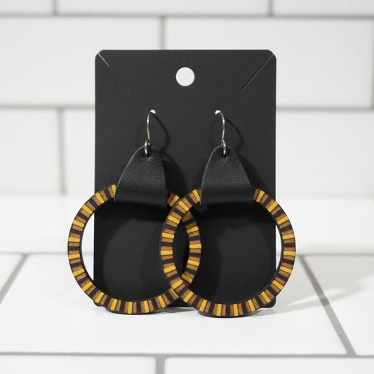 Pair of hoop earrings with black and yellow pattern on a dark surface