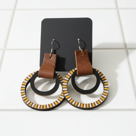 Pair of earrings with brown leather accents on a dark surface