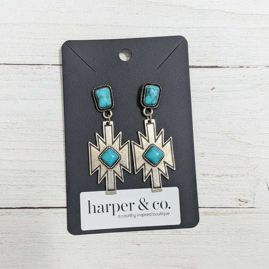 Pair of earrings with turquoise stones on a Harper & Co card against a wooden background